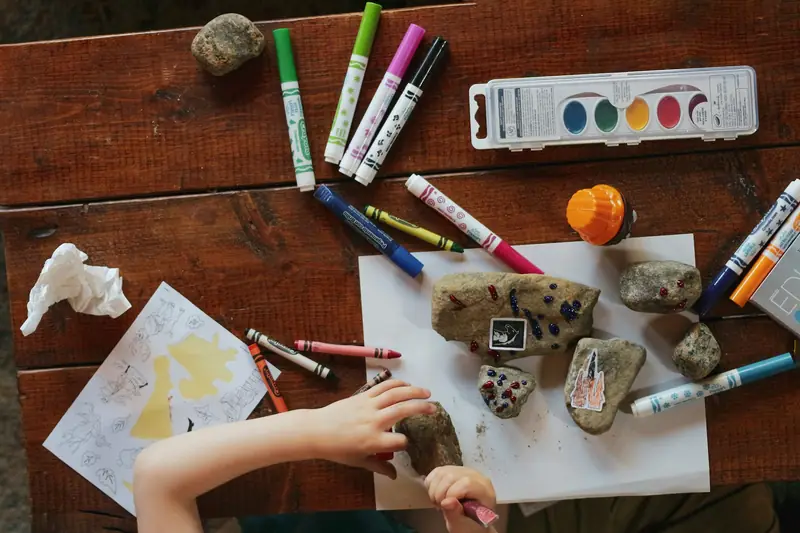 Paints, markers and painted stones on a wooden table