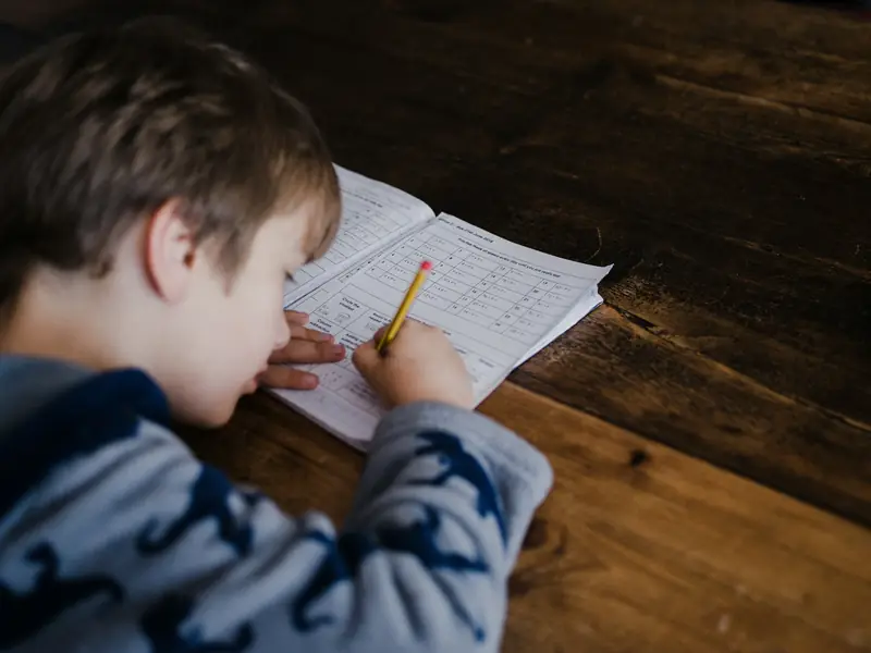 A boy writing in a workbook