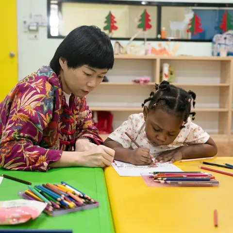 An educator and a child drawing together