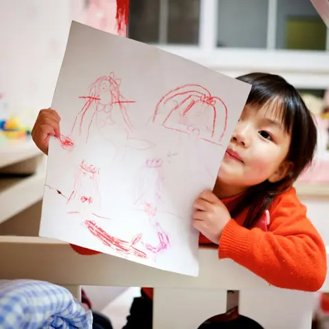 A girl holding up her drawing