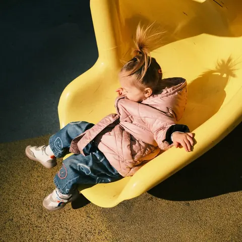 A toddler sliding down a yellow playground slide