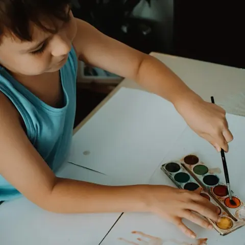 A child painting with watercolours at a table